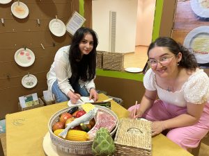 Öznur und Tamana malen ihr Lieblingsessen und hinterlassen damit Spuren in der Ausstellung, genauso wie die Kinder vor ihnen.